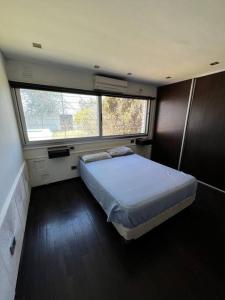 ein Schlafzimmer mit einem Bett in einem Zimmer mit einem Fenster in der Unterkunft Hermosa y amplia casa en Roldán in Roldán