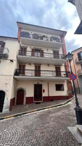 a tall building with balconies on a cobblestone street at A casa di Don Remo in Agnone