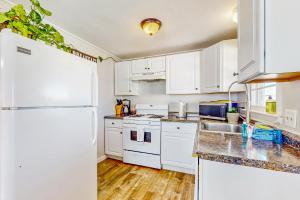 La cuisine est équipée de placards blancs et d'un réfrigérateur blanc. dans l'établissement The Cozy Cottage by the Ocean, à Hampton Beach