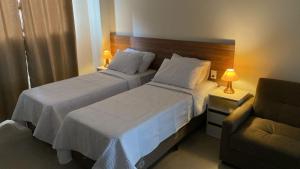 una habitación de hotel con 2 camas y una silla en Condomínio Kaimã en Matinhos