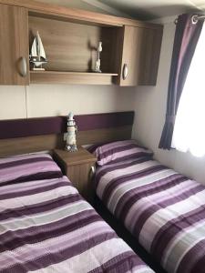 two beds in a room with purple and white stripes at Beautiful sea view 3 bedroomed Holiday Home Caravan in Exmouth