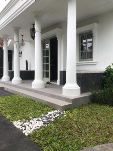a white house with white columns and a porch at Rumah Kenyeri in Denpasar