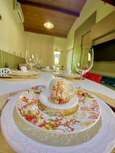 una mesa con un plato con una taza y copas de vino en Solar Água Apartaments, en Pipa