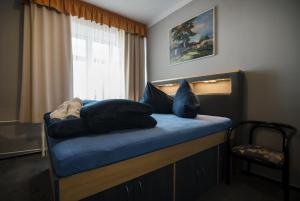 a bedroom with a bed with blue pillows and a window at Pension Ayky in Jablonec nad Nisou