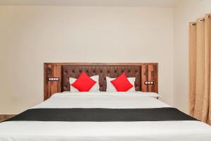 1 dormitorio con 1 cama con almohadas rojas en Collection O Hotel Surabhi, en Surūrnagar