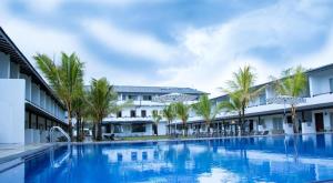 a large swimming pool with palm trees in front of a building at Rathna Beach Wadduwa in Kalutara