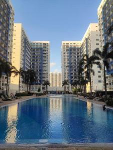uma grande piscina com palmeiras e edifícios em Casa Renta by John J. em Manila