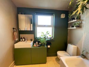 a green bathroom with a sink and a mirror at Cosy Room In Altrincham in Hale