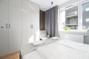 a white bedroom with a large bed and a window at Apartament przy Koscielnej in Poznań