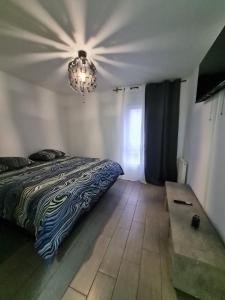 een slaapkamer met een bed en een kroonluchter bij Apt cosy village olympique in Saint-Ouen