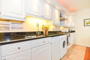 a white kitchen with a sink and a dishwasher at Stunning Ocean Views, The Priory in Shanklin