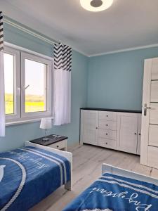 a bedroom with blue walls and a bed and a window at Siedem mórz in Gąski