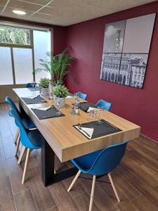 Cette chambre comprend une grande table en bois et des chaises bleues. dans l'établissement Campanile Saint Quentin, à Saint-Quentin