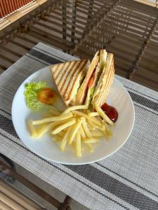 un plato blanco con un sándwich y papas fritas en Casa Ison Hotel, en Sablayan