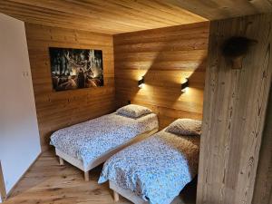 2 Betten in einem Zimmer mit Holzwänden in der Unterkunft Bois des Alpes in Annecy