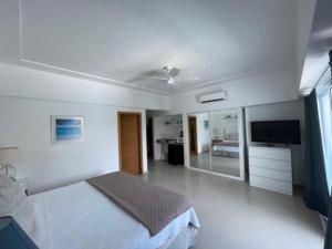 a white bedroom with a bed and a flat screen tv at Elegante Blue Marine Apartamento Juan Dolio in Juan Dolio