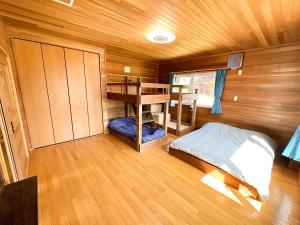 een kleine kamer met een bed en een bureau bij Base Shiraoi with Mall Onsen in Shiraoi