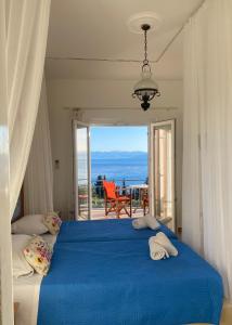 a bedroom with a blue bed with a view of the ocean at Panorama Notos in Nótos