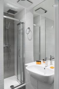 y baño blanco con lavabo y ducha. en Mornington Hotel London Victoria, en Londres