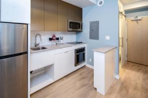 a kitchen with white cabinets and a stainless steel refrigerator at Micro Boutique Living Fredericton in Fredericton