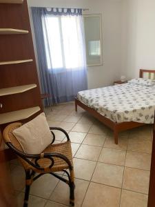 una camera con un letto e una sedia e una finestra di SPELU - Appartamento con terrazza fronte mare a Lido Marini