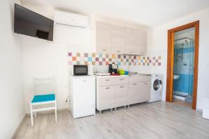 een keuken met witte kasten en een wasmachine en droger bij Camera Ponente - vista mare, spiaggia a 300m in Golfo Aranci