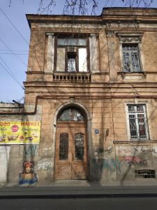 um edifício antigo com uma porta de madeira numa rua em Apartment Milena Tbilisi Onebedroom em Tbilisi