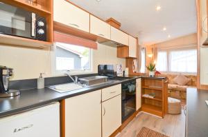 a kitchen with white cabinets and a black counter top at 'Sundowner' Fairways in Sandown