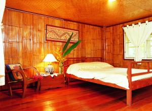 ein Schlafzimmer mit einem Bett, einem Tisch und einem Stuhl in der Unterkunft Yang Tone Farm Stay in Chiang Dao