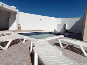een zwembad met twee witte stoelen naast een gebouw bij Villa phare 2 in Midoun