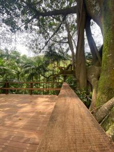 a wooden boardwalk with a tree and a fence at Fazenda São Miguel in Monte Alegre do Sul