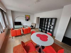 a living room with a table and red chairs at Astrid - apartments in Mechelen