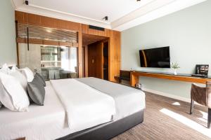 a bedroom with a white bed and a television at Select Hill Resort in Tirana