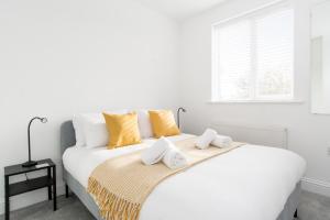 una camera da letto bianca con un grande letto bianco con cuscini gialli di Charming 3- Bedroom Terrace House with Netflix and Free Parking by HP Accommodation a Market Harborough