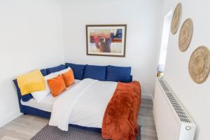 a bedroom with a blue bed with colorful pillows at Charming 3- Bedroom Terrace House with Netflix and Free Parking by HP Accommodation in Market Harborough