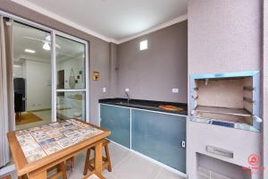 a kitchen with a counter and a table in it at BH28: 1 Quadra d Praia, Ar, Churrasqueira, Piscina in Ubatuba