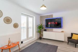 a living room with a tv on a wall at Charming 3- Bedroom Terrace House with Netflix and Free Parking by HP Accommodation in Market Harborough