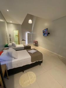 a bedroom with two beds and a tv on the wall at Pousada Aurora in Alto Paraíso de Goiás
