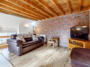 - un salon avec un canapé en cuir et un mur en briques dans l'établissement 1 Bed in Hay-on-Wye 81465, à Painscastle