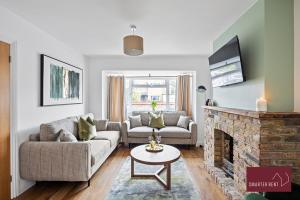 een woonkamer met een bank en een open haard bij Woking -Garden Driveway Parking 4Bed in Brookwood