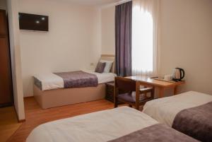 Habitación de hotel con 2 camas, escritorio y ventana en Hotel Basen, en Sisian