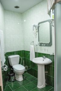 a green tiled bathroom with a toilet and a sink at Hotel Basen in Sisian