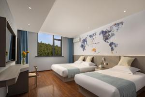 two beds in a room with a world map on the wall at Anlan Hotel Shangrao Wuyuan Cultural Plaza in Wuyuan