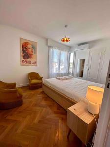 - une chambre avec un grand lit et une chaise dans l'établissement Cyrille Besset - Charmant T2 avec balcon, à Cagnes-sur-Mer