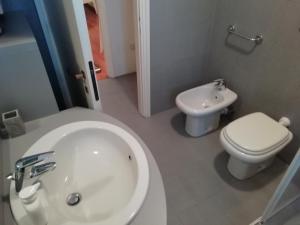La salle de bains est pourvue de toilettes blanches et d'un lavabo. dans l'établissement Lesa 'Il Parco', à Lesa