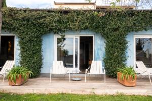 ein blaues Haus mit weißen Stühlen und Pflanzen in der Unterkunft Hotel Boutique Mas Passamaner in La Selva del Camp