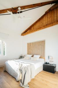 a white bedroom with a large bed and wooden floors at Hotel Boutique Mas Passamaner in La Selva del Camp