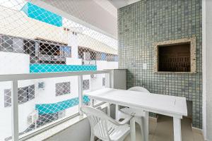 Apto c/ churrasq. e piscina - quadra mar - RMI201 في فلوريانوبوليس: طاولة بيضاء وكراسي في غرفة بها بلاط