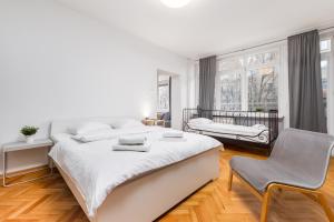 a white bedroom with a large bed and a chair at Apartament Wspólna by Your Freedom in Warsaw