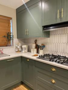 een keuken met groene kasten en een fornuis bij Charming Family Home with Gym in Henley on Thames